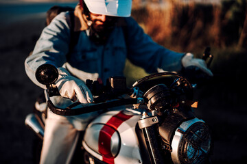 Chico moreno con moto tipo scrambler en la playa viajando 