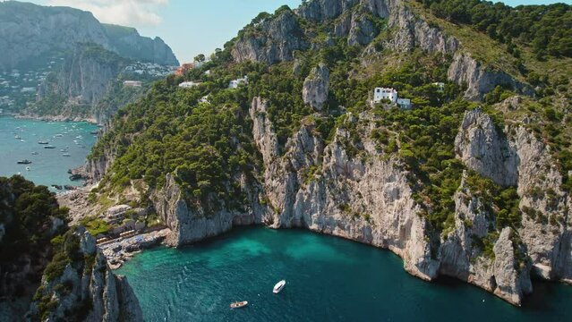 Cliffs on secluded cove with famous Da Luigi ai Faraglioni beach on Capri, italy. Sheer limestone rocks shelter a tranquil azure bay. Summer vacations.