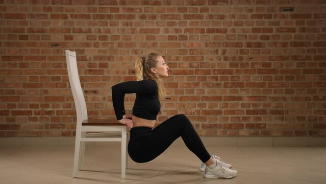Capturing the essence of arm toning, a fitness expert performs chair dips in a minimalist gym, targeting triceps and demonstrating impeccable form. Camera 8K RAW. 