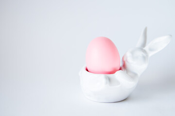 Easter egg lies in white porcelain stand in shape of bunny on background, Happy Easter tradition