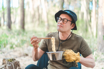キャンプ飯でインスタントラーメン・袋麺を食べるキャンパーの男性
