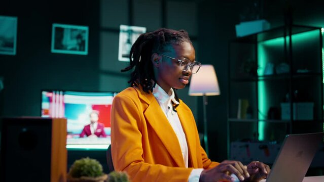 African american student writing reports for her final course essay, doing homework in her apartment. Girl communicating with professors via email or messaging platforms to correct facts. Camera B.