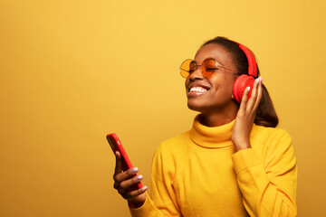 afro american female with dances in rhythm of melody, listens loud song in headphones, holds...