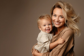 beautiful young blonde mother hugging a small smiling baby on a beige background, studio, portrait, children, woman, child, toddler, kid, place for text, parent, family, mother's day