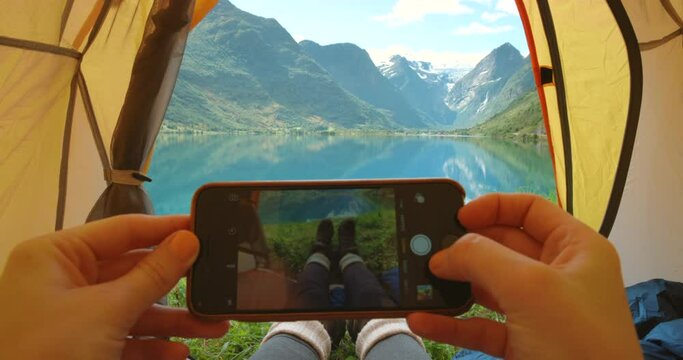 Feet, camping tent and photograph on vacation, travel and mountain view on morning in nature. Person, smartphone and pov on holiday, picture and social media on outdoor adventure at lake or river