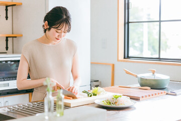 キッチンで料理・家事をする若い女性・妻・主婦（包丁・切る・野菜）
