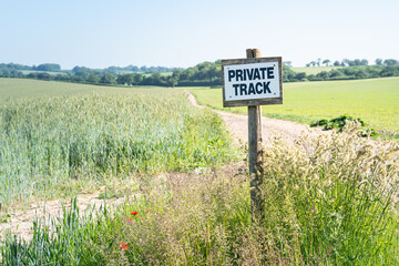 Wooden sign on rural farm agricultural land denoting a pathway as a private track no public access