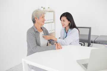 Asian doctor talk with old female patient about disease symptom, doctor use stethoscope listening...