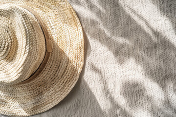 Fototapeta na wymiar A straw hat on a beach mat under the shadows of a palm leaves. Relaxed summer scene, vacation, sun, sea.