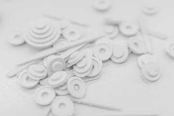 Scattered white plastic parts with central circular ridges on a white surface.