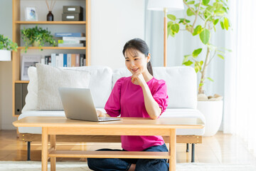 自宅でノートパソコンを操作する若い女性