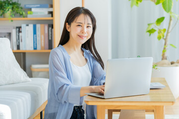 自宅でノートパソコンを操作する若い女性