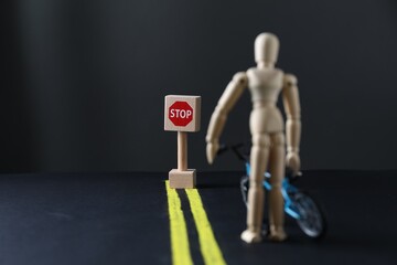 Development through barriers overcoming. Road Stop sign blocking way for wooden human figure with toy bicycle, space for text