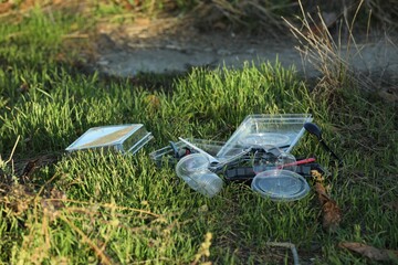 Used plastic tableware on grass outdoors. Environmental pollution concept