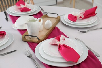 Color accent table setting. Plates, cutlery and pink napkins, closeup