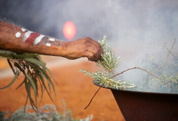 Human hand with green branch of eucalyptus, smoke and fire, the smoke ritual rite at a indigenous community event in Australia