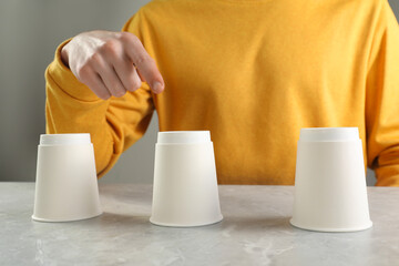 Man playing shell game at light marble table, closeup