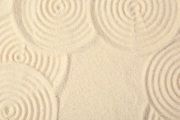 Fototapeta na wymiar Zen rock garden. Circle patterns on beige sand, top view