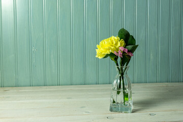 Single yellow carnation with greenery in a small delicate vase.