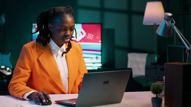 Focused student engaging in her studies at home office with laptop, determined to excel in her academics and graduate school. Hardworking girl reviews course materials and lecture notes. Camera A.