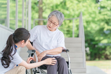 車椅子に乗る高齢者と介護士（股関節）
