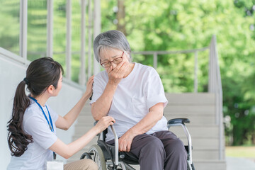 咳をする車椅子に乗った高齢者と介護士（喘息・吐き気）
