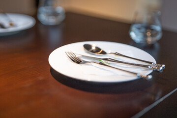 Simple dining table, table setting, glasses, metal cutlery, white ceramic plates, platters, simple style restaurant decoration, green management, environmentally friendly enterprise