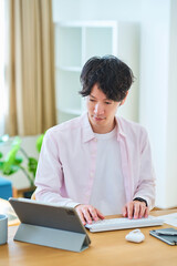Fototapeta premium 部屋でパソコンの操作をする若い男性