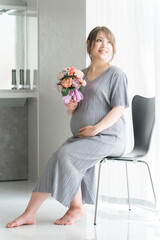 花束・ブーケを持つ妊婦・マタニティフォト（椅子に座る）
