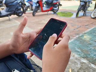 A man's hand is operating a smartphone. In one of the photos, his hands can be seen concentrating on typing or swiping on the cellphone screen, giving the impression of using technology.