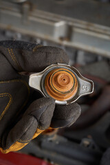 close-up of mechanic holding an old rusty and muddy car radiator cap, rust buildup on vehicle...
