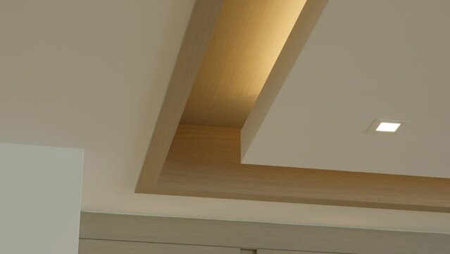 Corner of multilayered white suspended ceiling in complex shape with square halogen spots lamps and drywall construction decorating empty room of renovated apartment