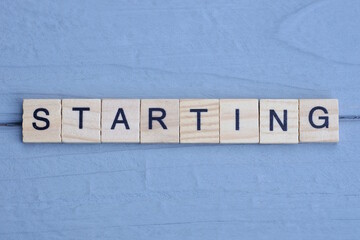 text the word starting from brown wooden small letters with black font on an gray table