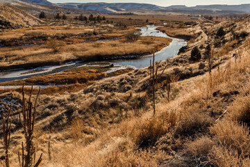Ice covered stream and snow powdered mountains in sunny day in Idaho wilderness