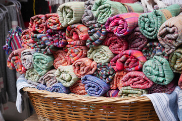A storage basket made of wood filled with an assortment of towels