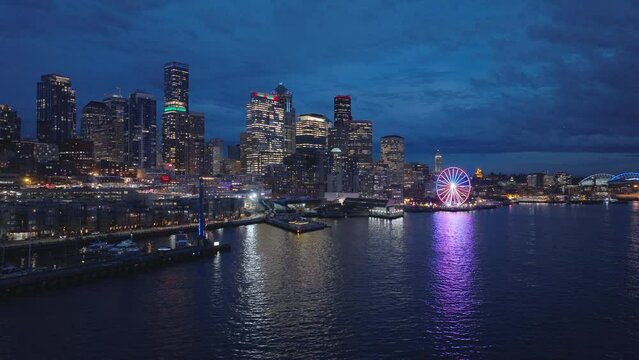 Downtown Seattle at dark winter night light. 4K b roll drone shot of cityscape night scene. Illuminated night city USA. Aerial panorama of seafront and financial district skyscrapers and buildings