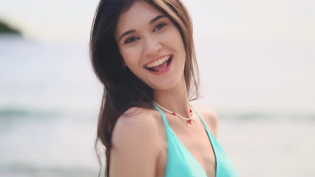Beautiful young woman wearing a bikini smiles happily on a relaxing day on the beach