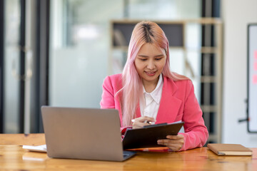 Accountant asian women at desk using laptop document archives on folders papers and calculator for...