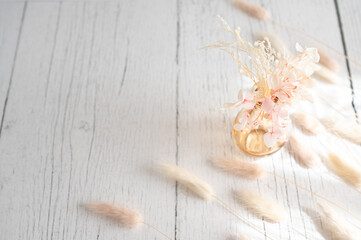 Vintage style of pastel natural colored, beige, and pink foxtail and dried flower in a vase against a white wooden backdrop with space for text. Spring and Autumn inspiration