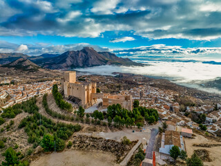 Aerial view of Velez Blanco hilltop medieval castle with square tower, restored Gothic palace above the town with dramatic sky - obrazy, fototapety, plakaty