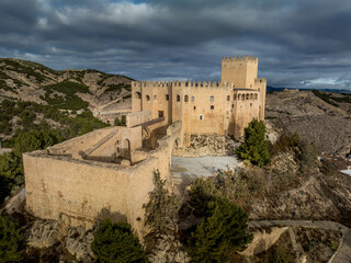 Aerial view of  Velez Blanco castle on a hilltop and town with one or two floor houses whitewashed walls and tiled roofs with dramatic cloudy sky in Andalusia Spain