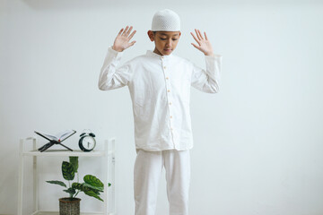 Young Asian muslim boy praying, raising hands and doing first movement in salat or takbiratul ihram...