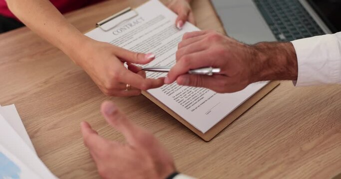 Closeup of executive hands holding pen and pointing to sign contract in office