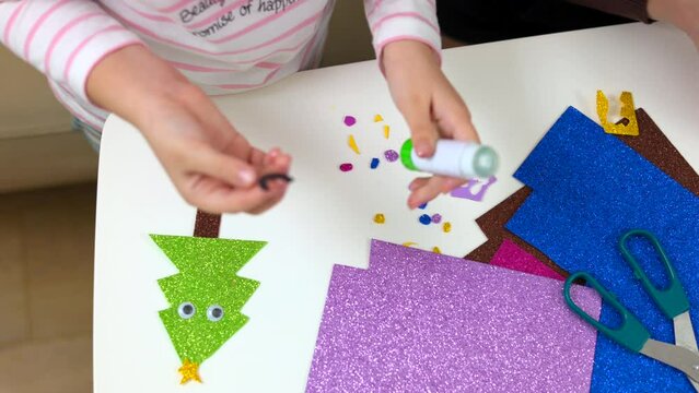Mother teaches her children to do craft item from colored paper