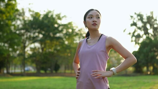 Fitness Asian woman looking at watch waiting for friend's appointment before running training during morning exercise, woman checking heart rate from watch after running, healthy lifestyle concept.