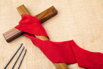 Jesus Wooden cross wrapped with red cloth next to nails. Catholic Christians Good Friday Ceremony....