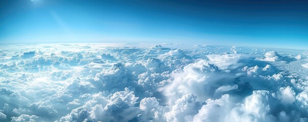 A stunning aerial panorama of dense cumulus clouds bathed in sunlight, with a clear blue sky above. - Powered by Adobe