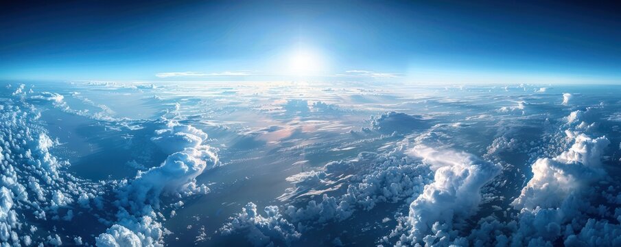 A stunning aerial panorama of dense cumulus clouds bathed in sunlight, with a clear blue sky above.
