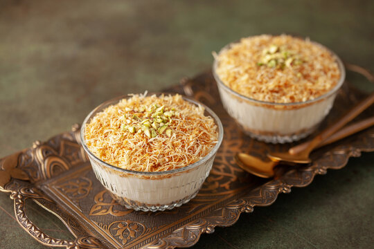 Traditional milky crispy Ramadan dessert custard pudding with roasted kadayif and diced pistachio . Kadayifli Muhallebi