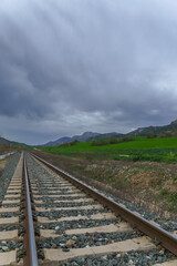 Fototapeta premium train track with mountainous landscape in the background and stormy cloudy sky